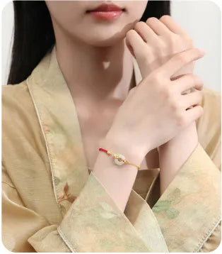 Close-up of a women's retro bracelet with a Hetian Jade stone, red cord, and a gold Koi fish safety buckle on a 925 silver chain.