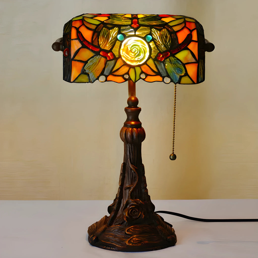 Tiffany table lamp with coloured stained glass shade and resin base on wooden desk