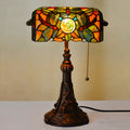 Tiffany table lamp with coloured stained glass shade and resin base on wooden desk