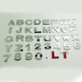 3D metal car letter sticker in zinc alloy, shown in black and silver finishes, approx. 2.5 cm in size.