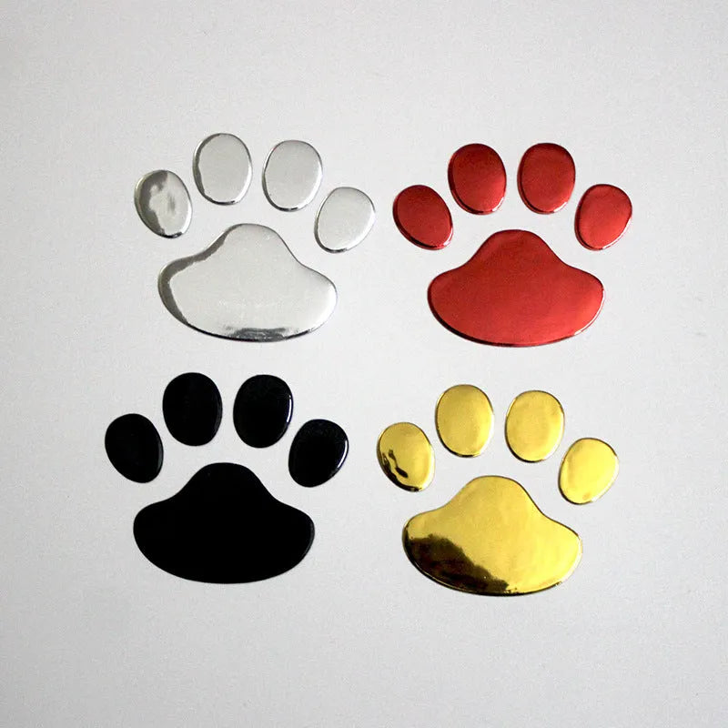 Close-up of a black PVC car sticker with dog footprints and a hand-shaped brush texture on a car bumper.