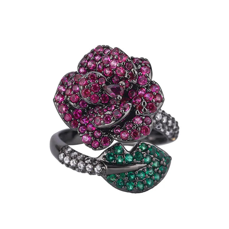A black gold geometric flower ring with simulated red corundum stones on a model's hand.