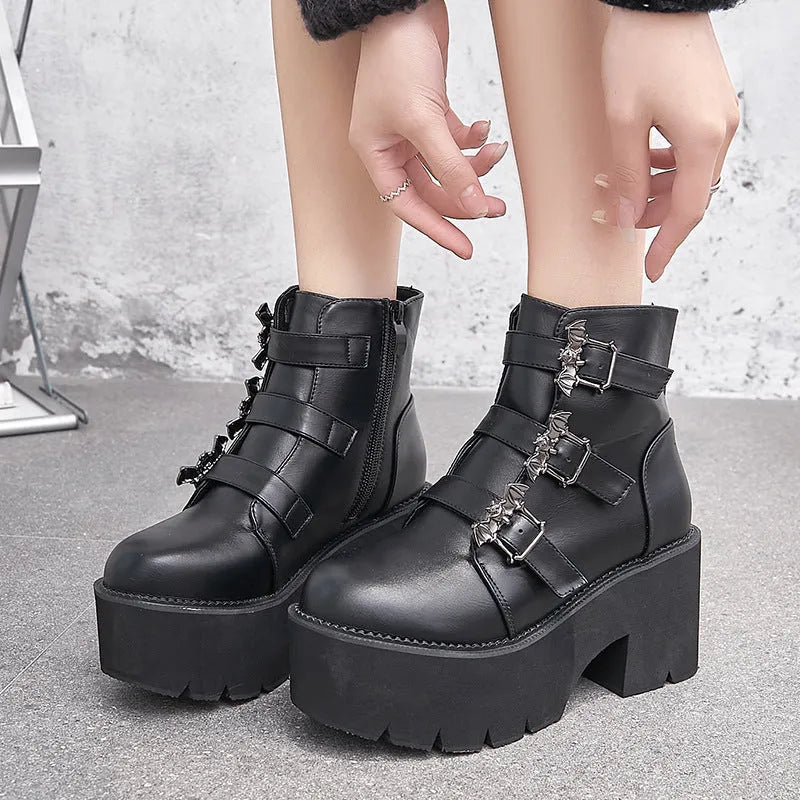 Black women's punk ankle boots with bat buckle detail, chunky heel, and side zipper.