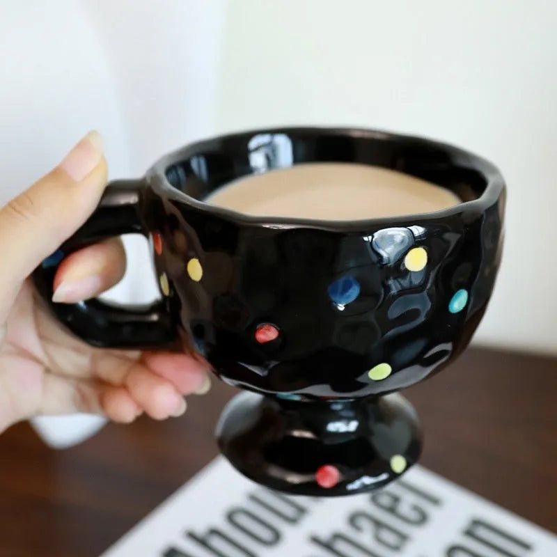 Hand-pinched irregular shaped ceramic mug in a solid colour, shown on a surface.