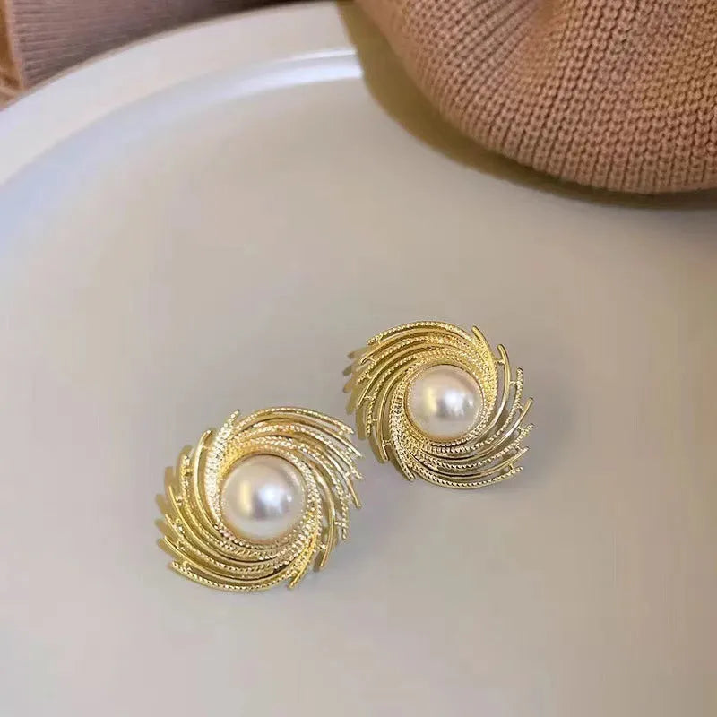 A pair of vintage-inspired pearl-coloured floral drop earrings with an irregular design on a white background.