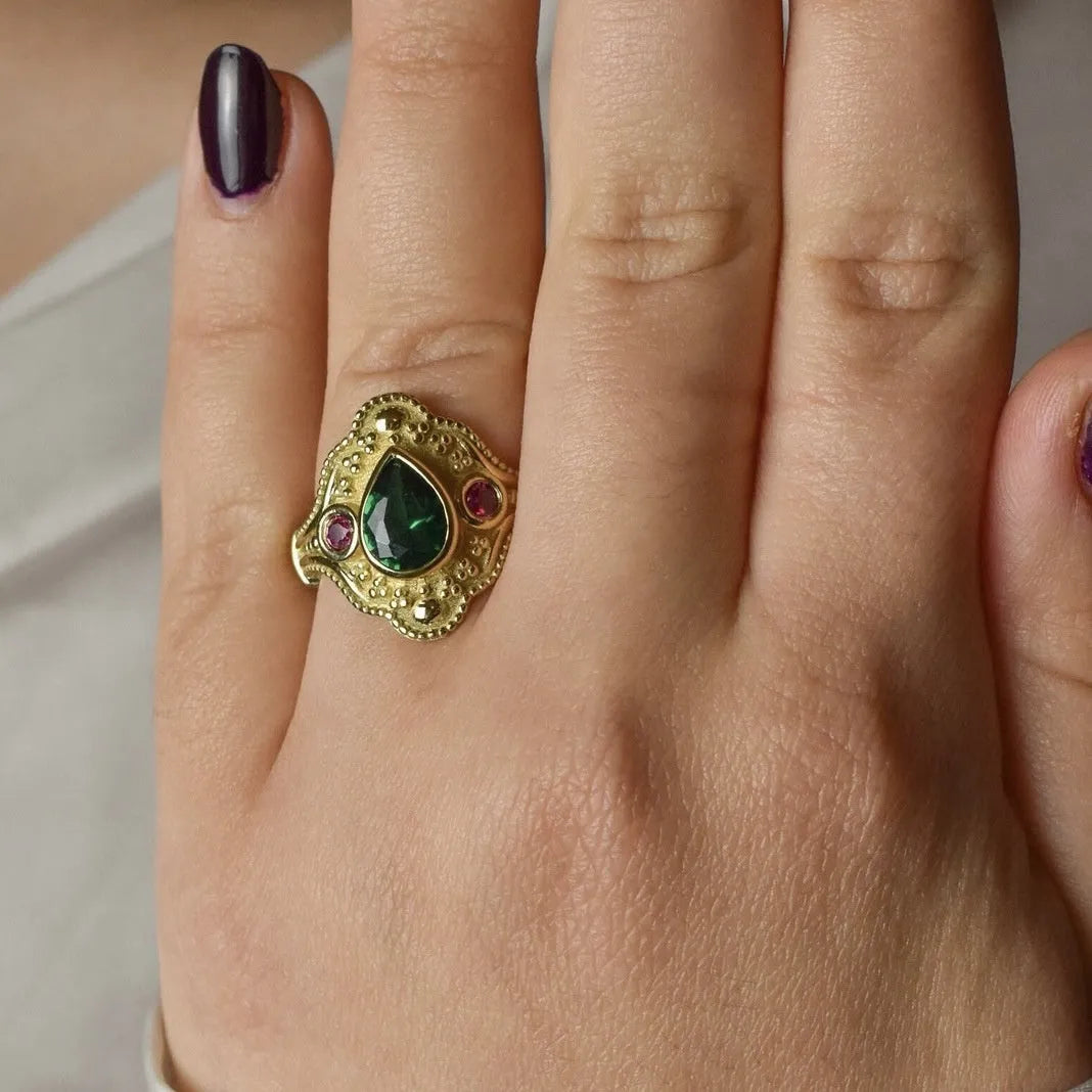 Gold-coloured geometric women's ring with an electroplated finish on a grey background.