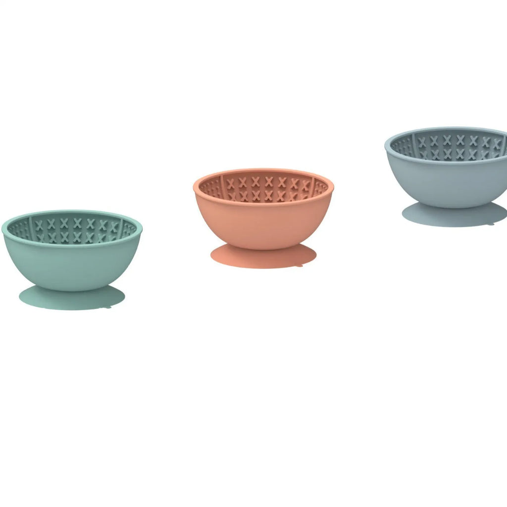 Cyan silicone pet licking mat and slow feeder bowl with suction cup base on a table.