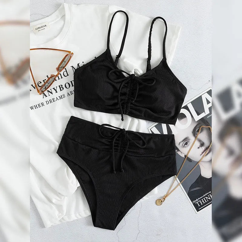 Black women's bikini swimsuit with sling top and high-waisted shorts on a white background