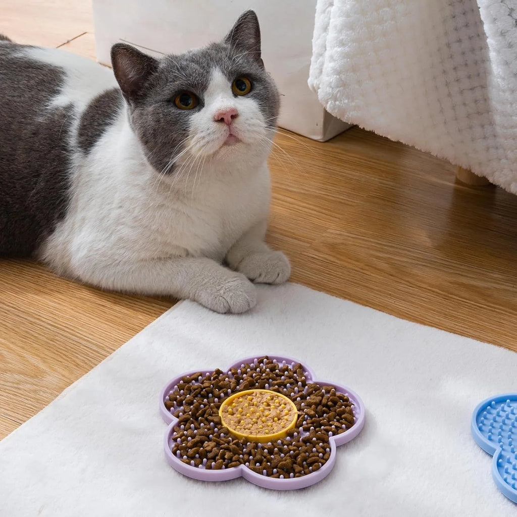 Flower-shaped silicone dog lick mat in pink with suction cups on the underside, shown on a tiled floor.