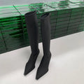 Women's black pointed toe below knee boots with back zipper and stiletto heel on grey background