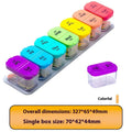 Extra large white plastic pill dispenser with 14 removable rainbow-coloured grid compartments open on a table.