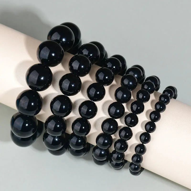 Adjustable sliding knot obsidian bracelet in hand with choice of black, rainbow eye, and silver crystal beads