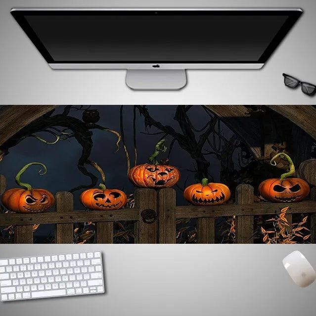 Oversized rectangular Halloween-themed mouse pad on a desk, showing one of 28 graphic designs.