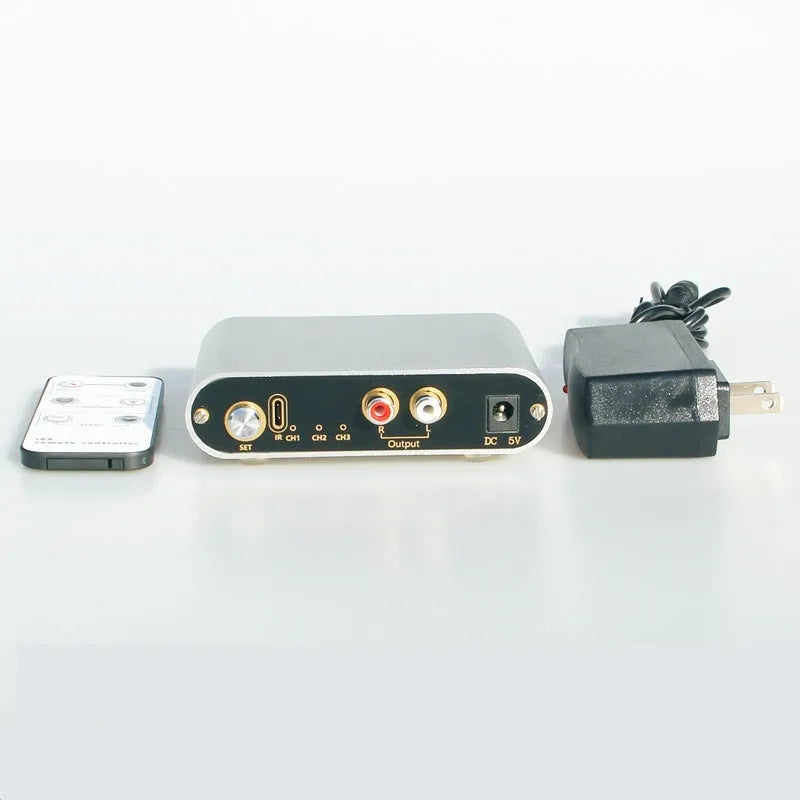 Silver audio source selector switch unit with infrared remote control for routing multiple audio signals.