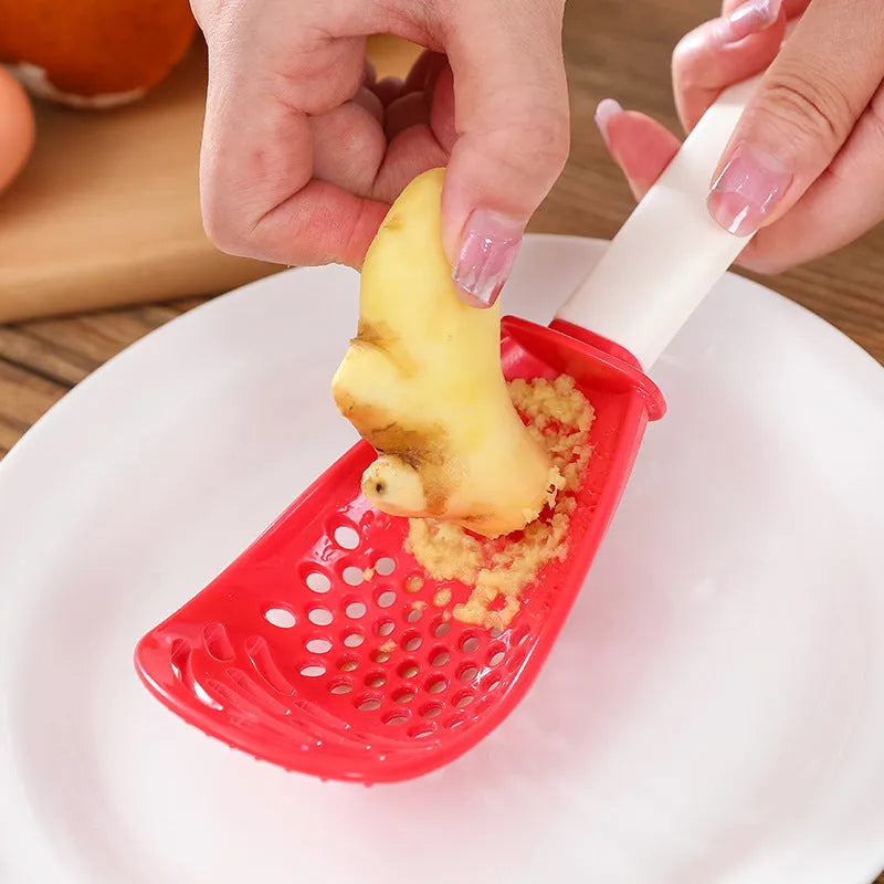 Red and black multifunctional plastic cooking spoon with serrated grinding edge and half-enclosed rice scoop head.