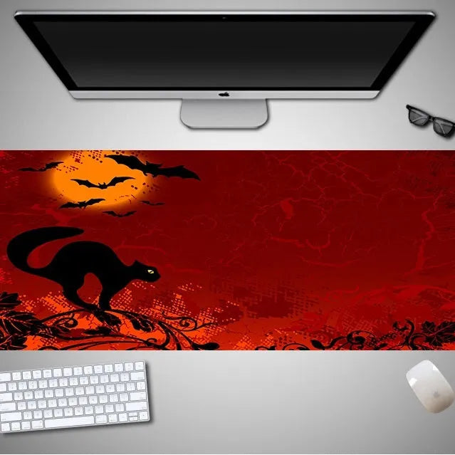 Oversized rectangular Halloween-themed mouse pad on a desk, showing one of 28 graphic designs.