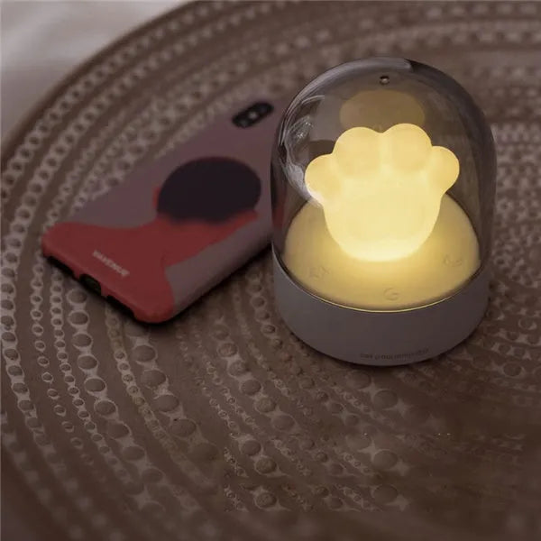 Grey and pink cat paw shaped USB rechargeable night light with music box function on desktop