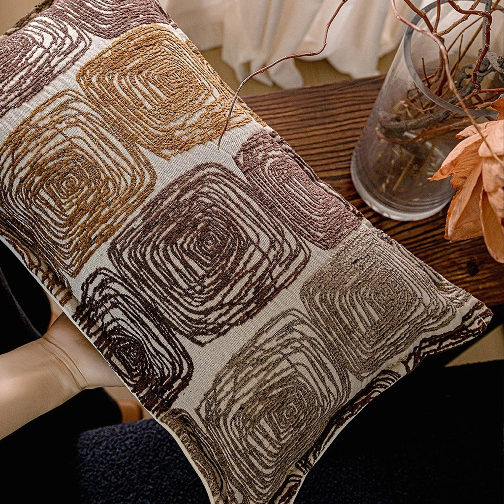 Cream and coffee-coloured abstract geometric coil pattern on a square pillow cover.