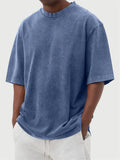 Man wearing a loose-fit, stone-washed distressed men's short sleeve T-shirt in a solid colour.