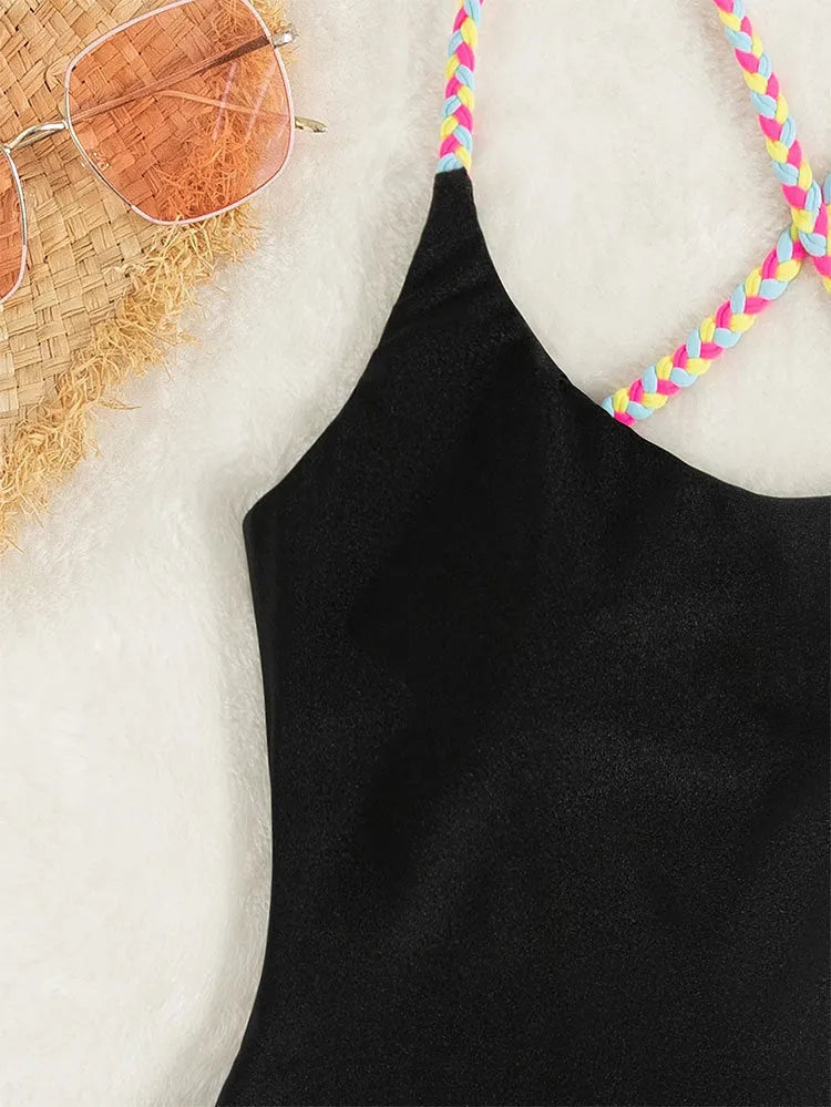 Black solid colour backless one-piece swimsuit for women on a hanger.