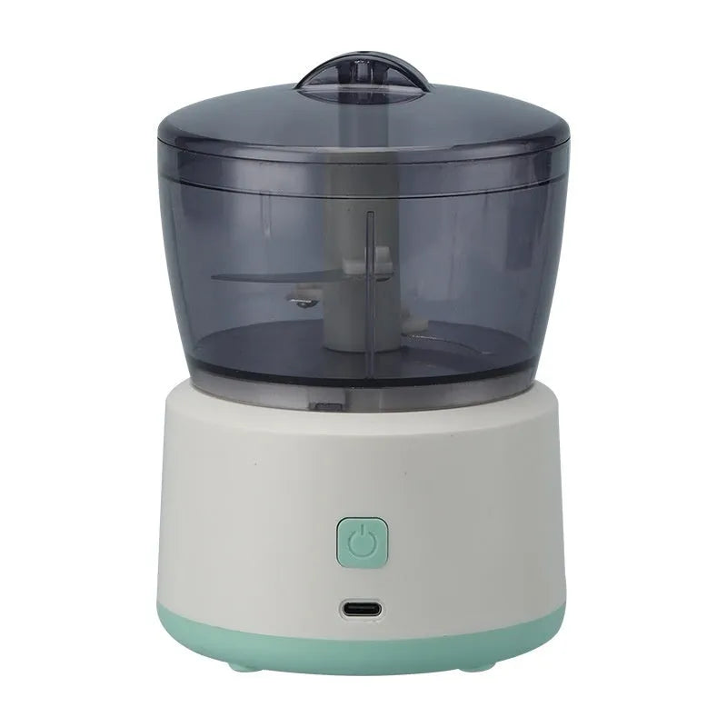 White or light green USB rechargeable mini electric meat grinder with transparent cup on anti-slip pad.