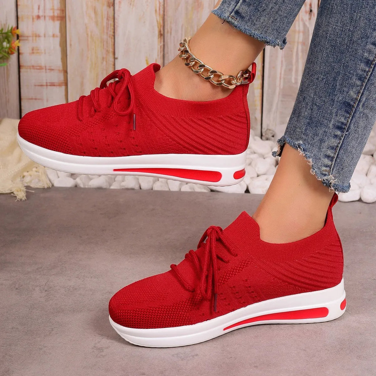 Women's low-top lace-up sneakers in red, black, or blue with a fly-knit texture and round toe.