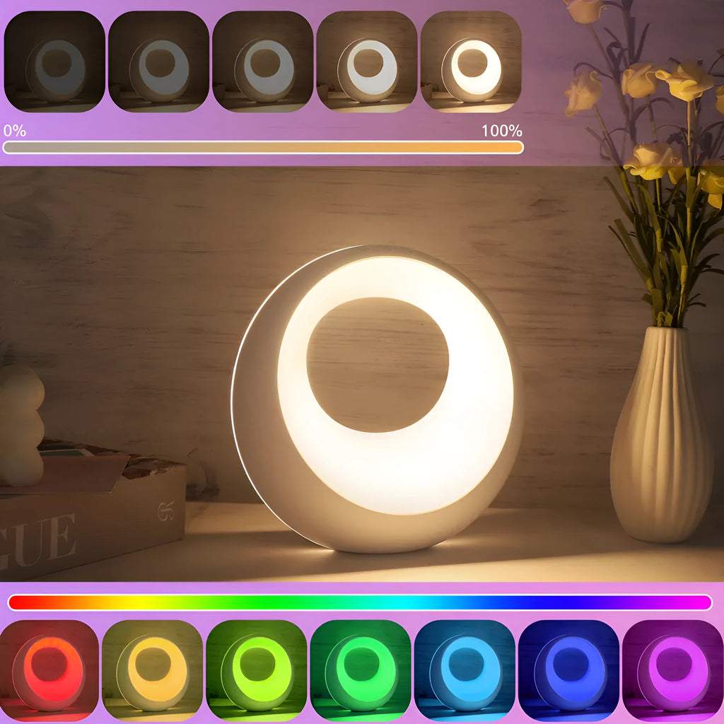Small white RGB colour changing desk lamp with remote control on a wooden surface.