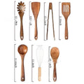 A set of seven wooden kitchen utensils including various spoons and spatulas on a table.