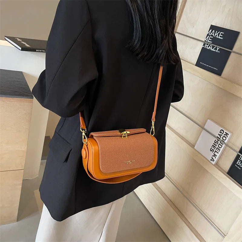 Structured women's PU leather messenger bag in a horizontal square shape with contrast stitching on a table.