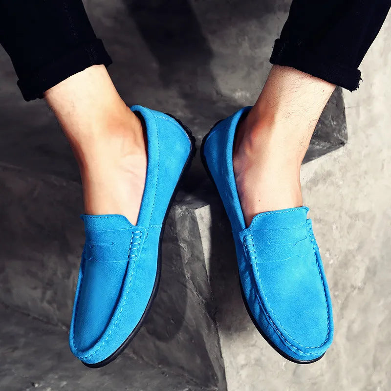 Men's brown suede casual loafers with a round toe, flat rubber sole, and visible stitching on a white background.