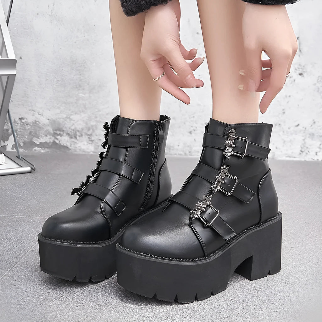 Black women's punk ankle boots with bat buckle detail, chunky heel, and side zipper.