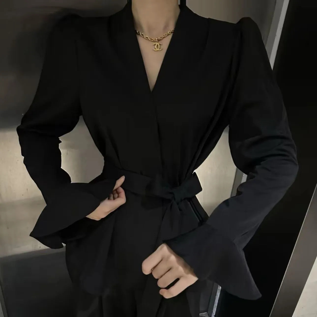 Women's black French-style shirt with an irregular collar, long flared bell sleeves, and a tied front closure.