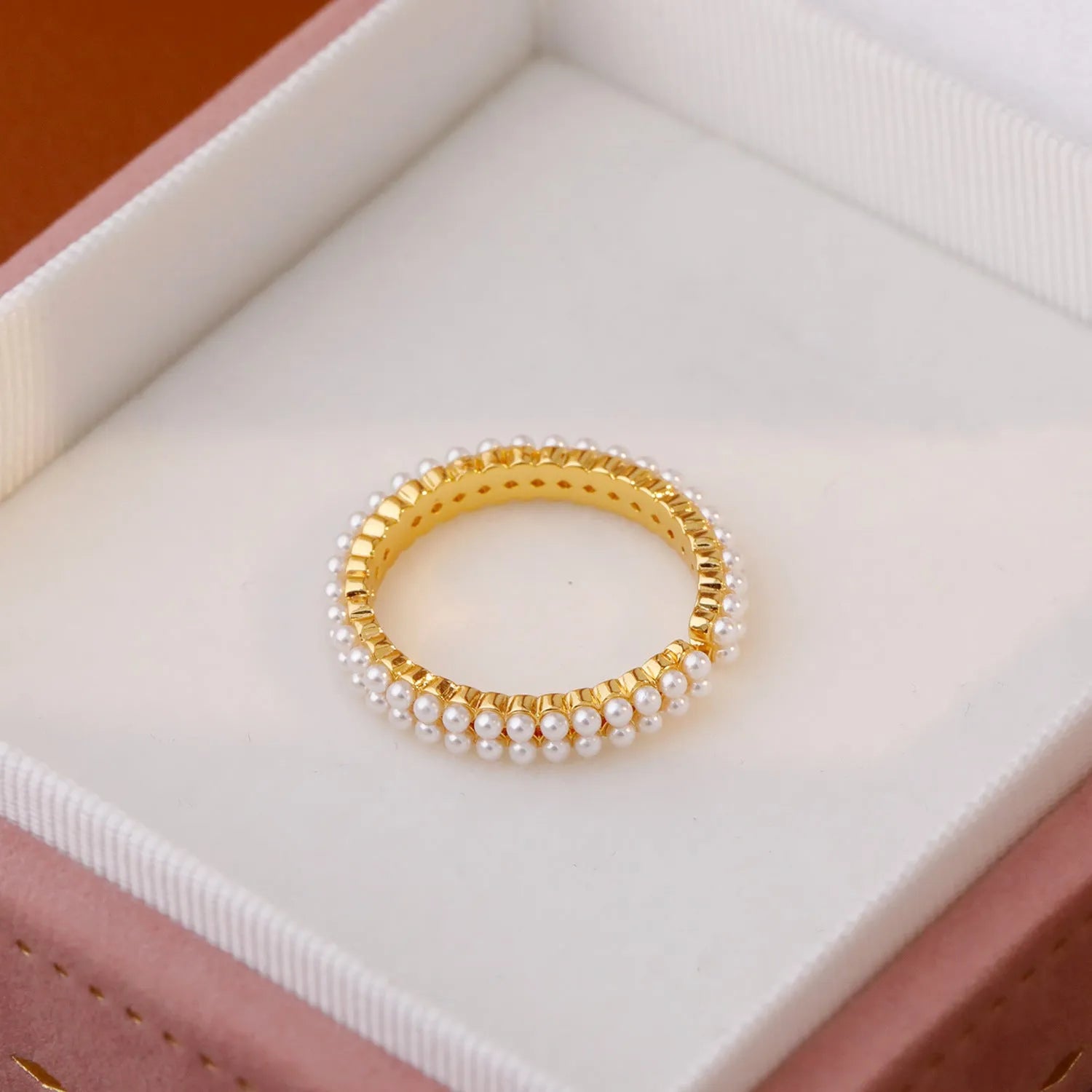 Gold geometric open ring with pearl detail on a model's finger.