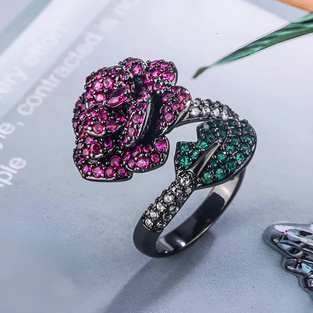 A black gold geometric flower ring with simulated red corundum stones on a model's hand.