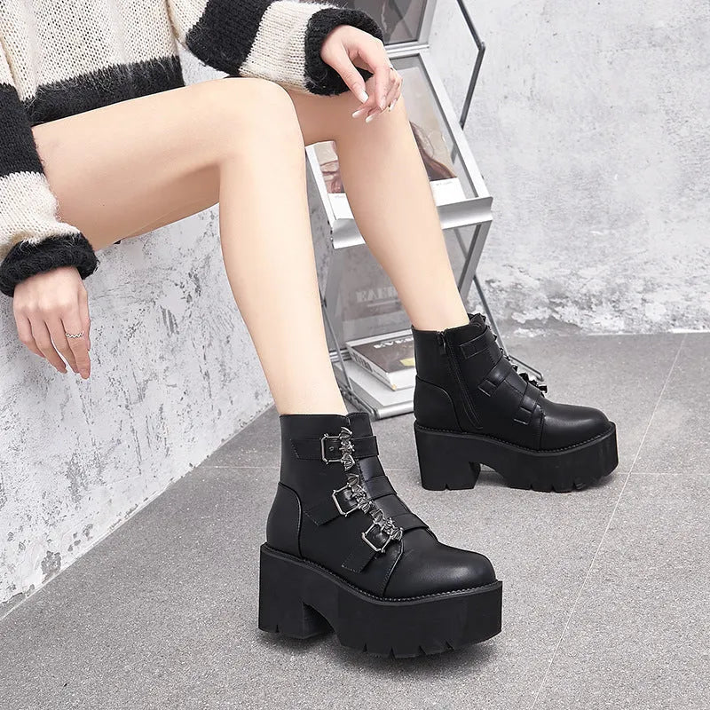 Black women's punk ankle boots with bat buckle detail, chunky heel, and side zipper.