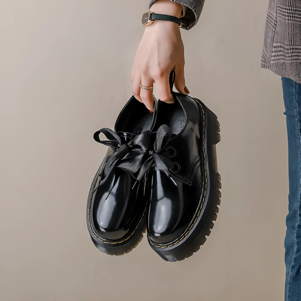 Women's black thick-soled lace-up shoes with white ribbon cross strap details on a superfine fibre upper.