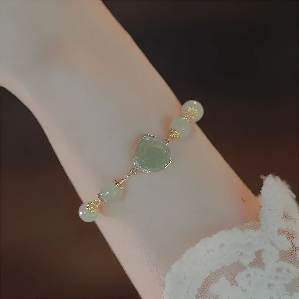 Close-up of a women's bracelet with a handmade Hetian Jade rose flower on a 14K gold plated band.
