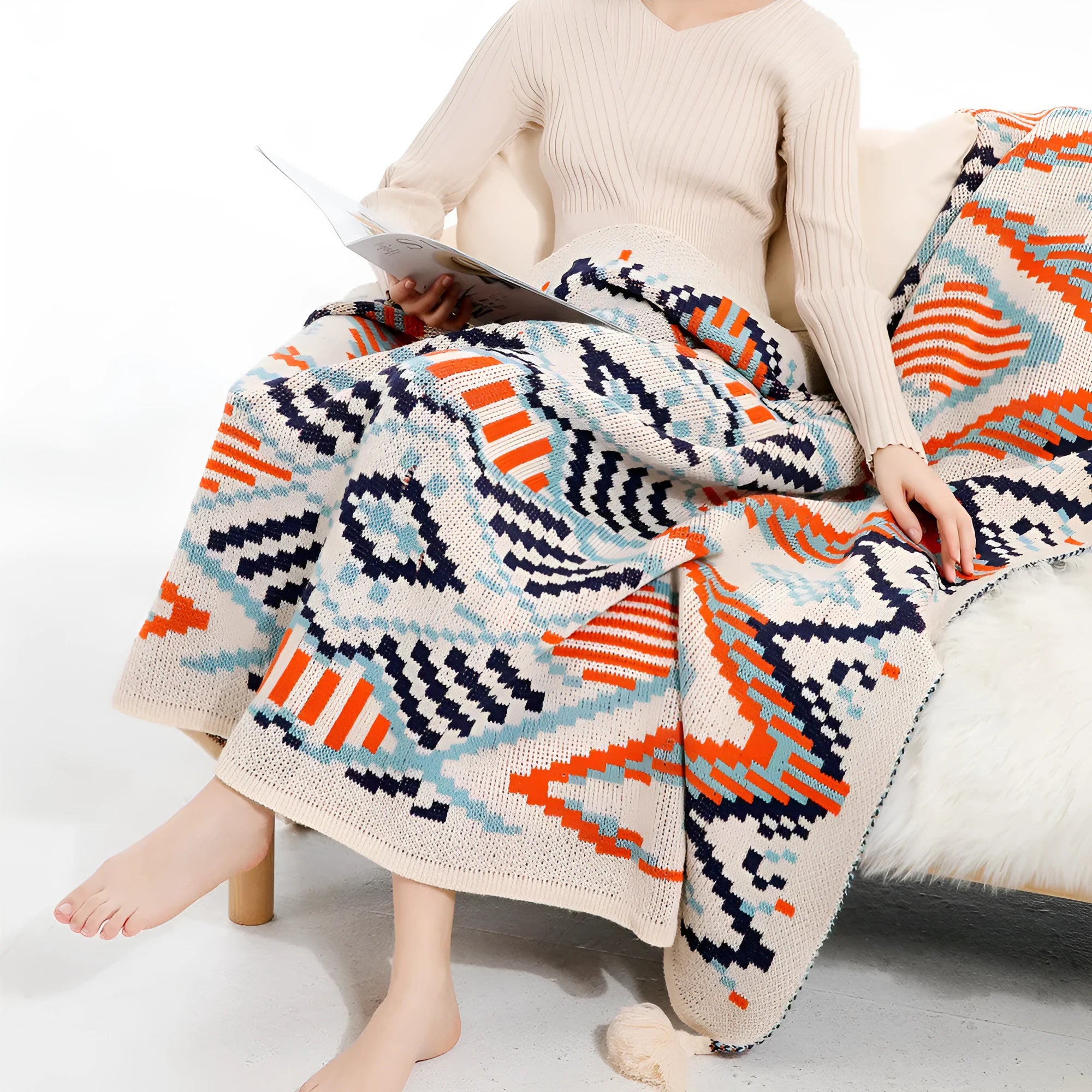 Bohemian style acrylic sofa blanket with tassel fringe in a geometric blue and pink pattern.