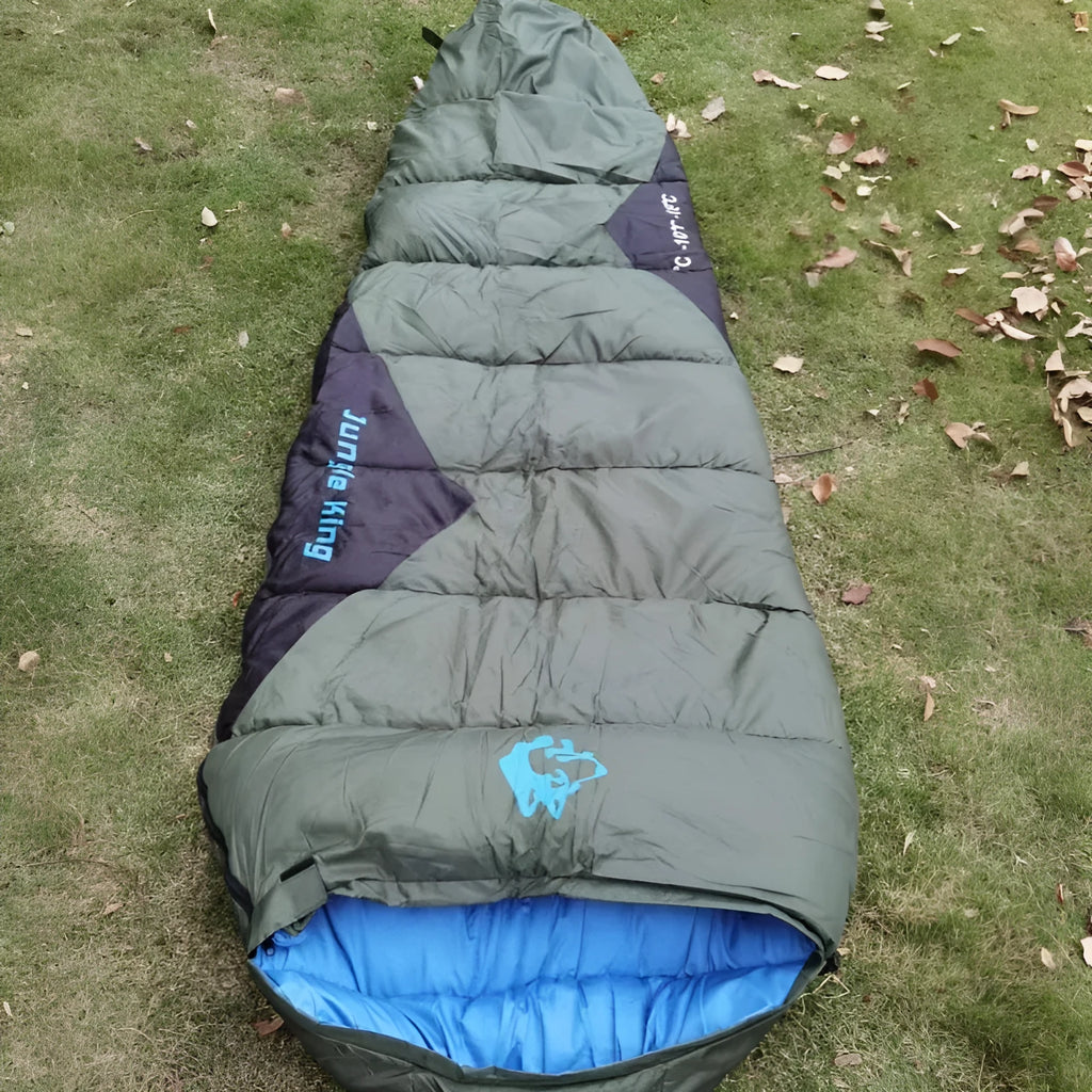 Brown cotton camping sleeping bag partially rolled next to its grey compression storage sack.