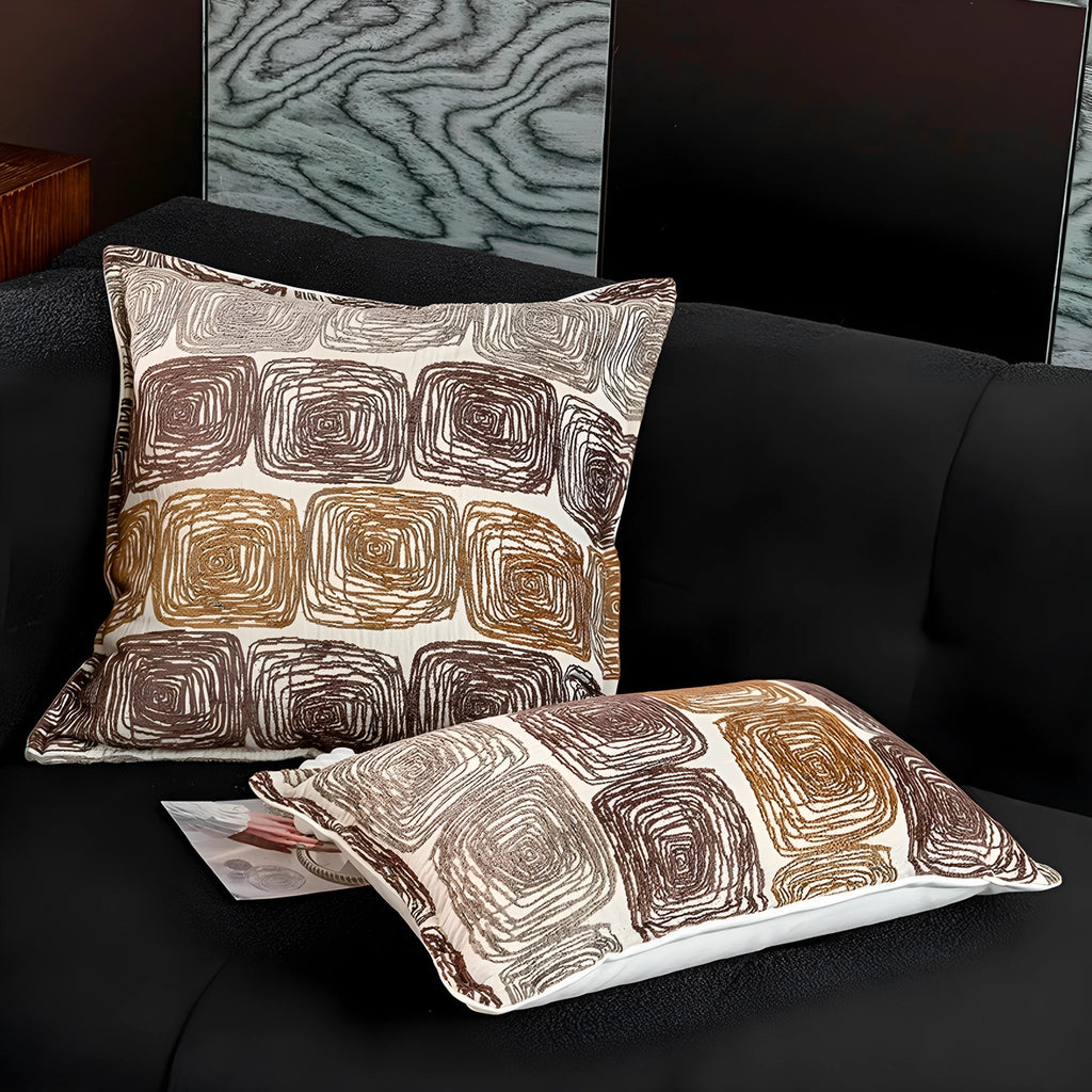 Cream and coffee-coloured abstract geometric coil pattern on a square pillow cover.