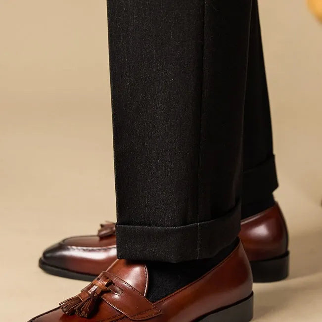 Men's black and brown genuine leather tassel loafers on a white background.