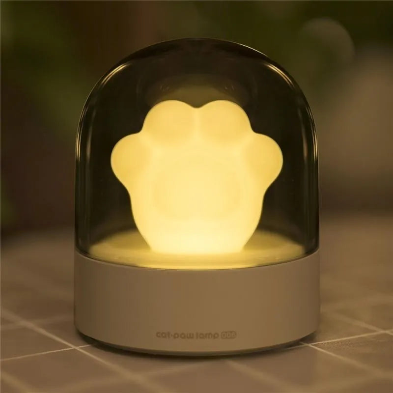 Grey and pink cat paw shaped USB rechargeable night light with music box function on desktop