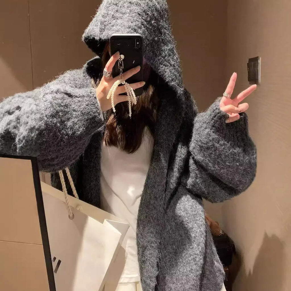 A woman wearing a thick, loose-fit hooded cardigan sweater in a milky white colour.