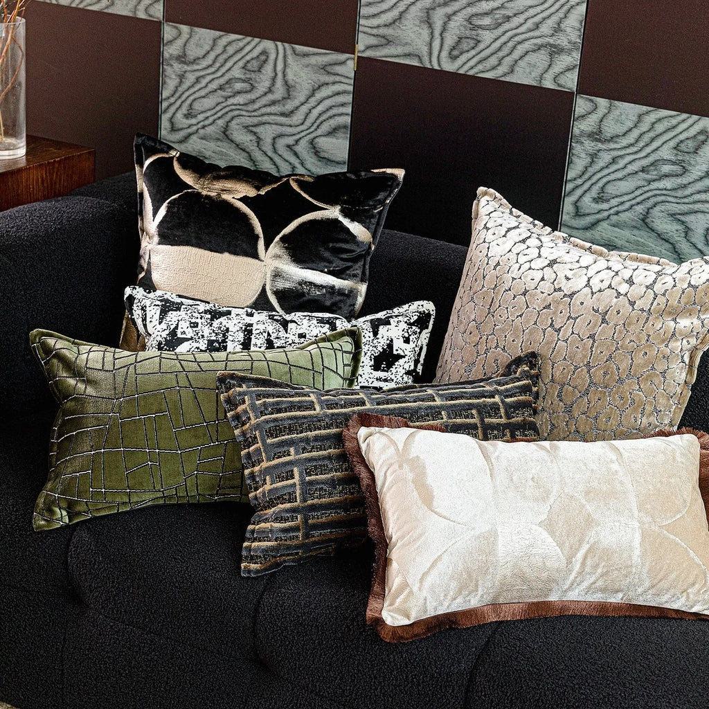 Black and gold abstract patterned square decorative pillow with a flannel cover on a grey sofa.