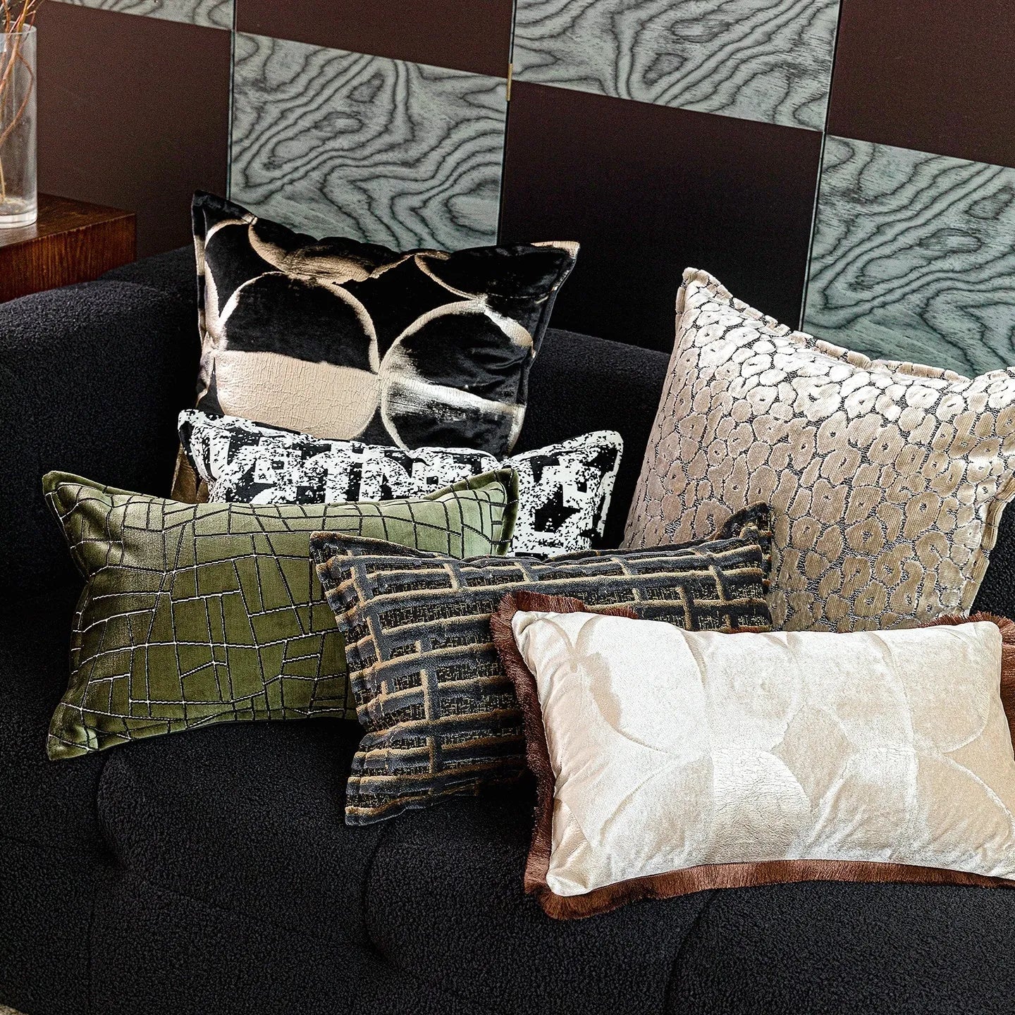 Black and gold abstract patterned square decorative pillow with a flannel cover on a grey sofa.