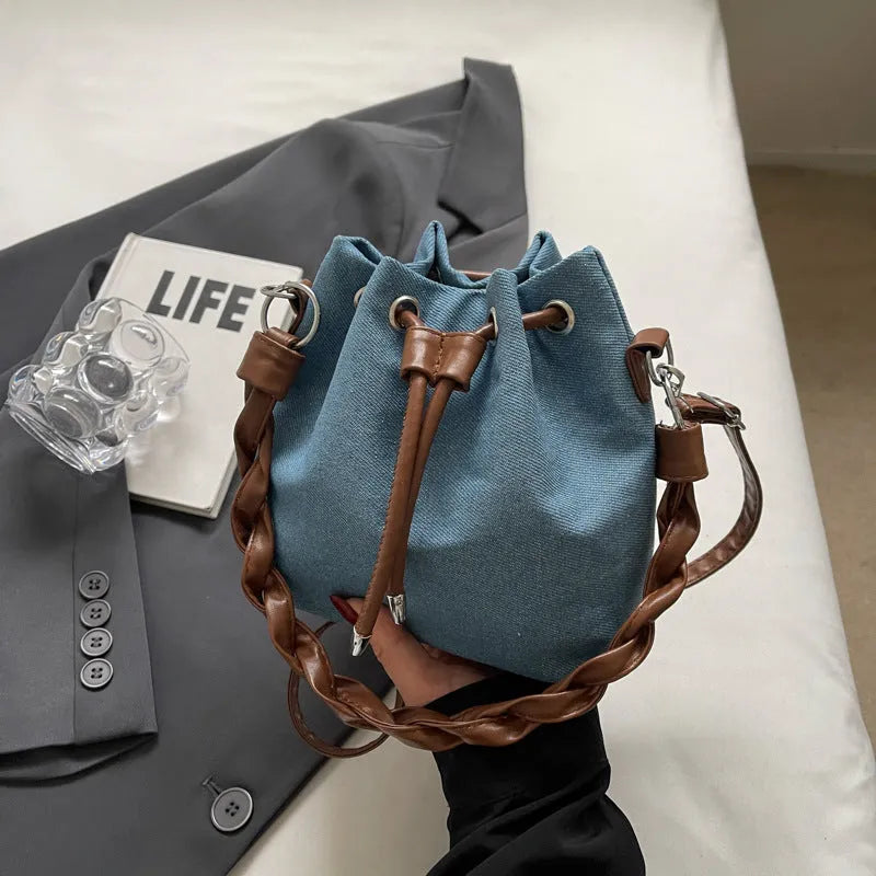 Blue synthetic leather cross body bucket bag with medium-soft structure and optional hanging ornaments