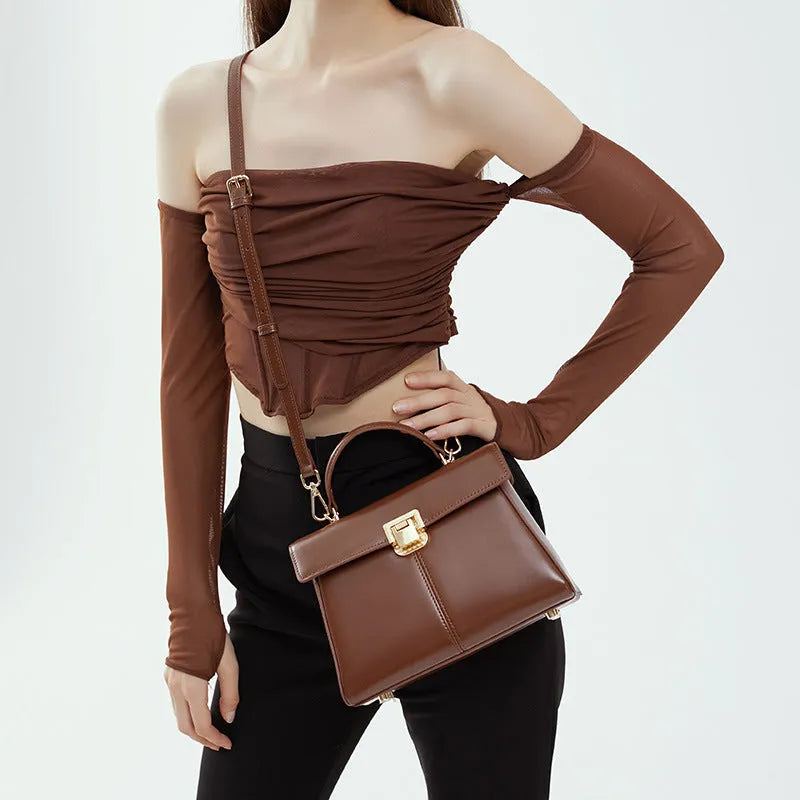 Women's black leather shoulder bag with vachette clasp showing horizontal square shape and shoulder strap