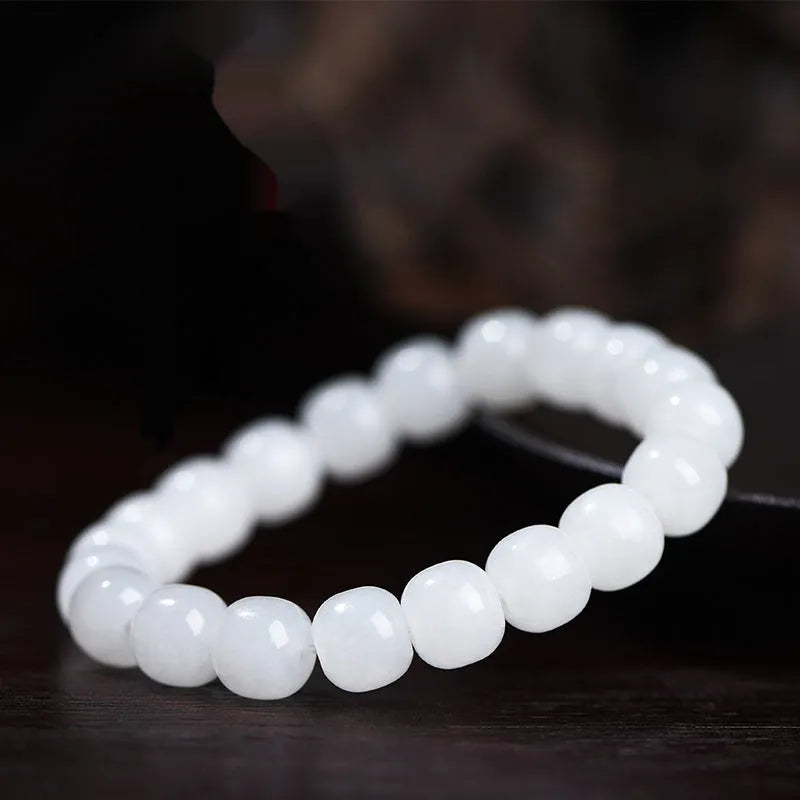 White Hetian jade barrel bead bracelet on a wrist, showing unisex casual style.