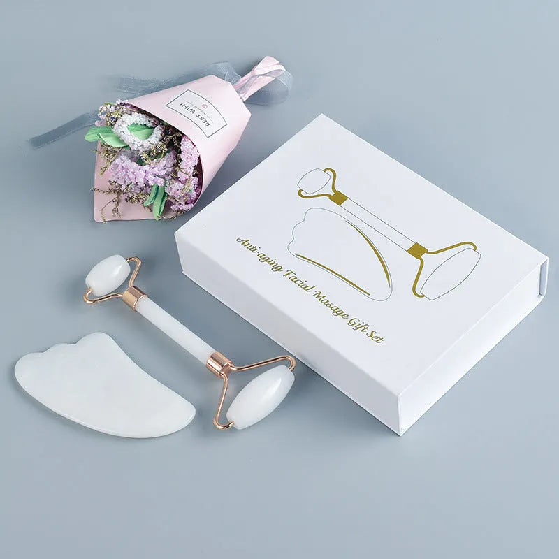 Natural white jade roller and gua sha scraping tool set presented on a wooden storage board.