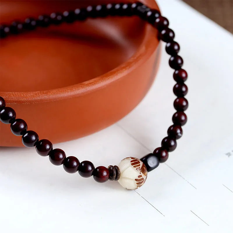 Rosewood bracelet with floral beads and circle pendant options on wooden background